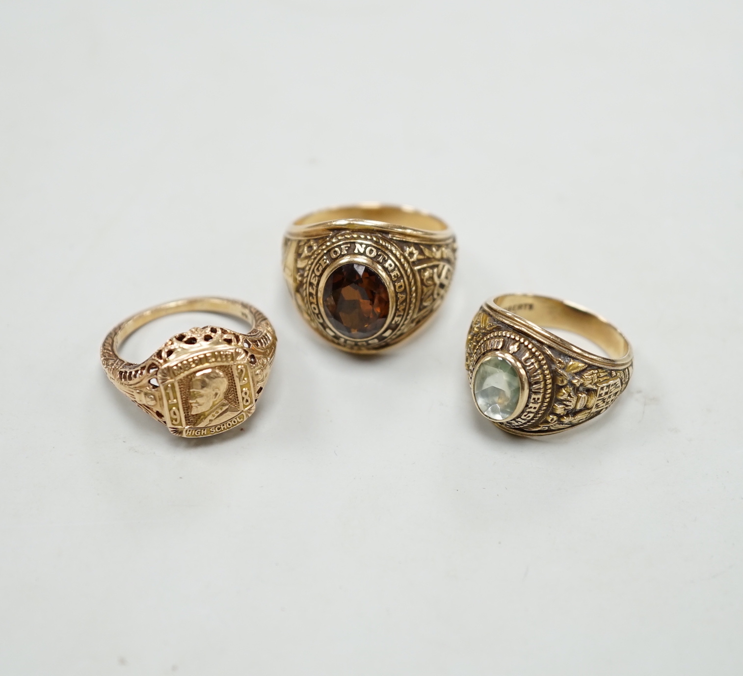 Three assorted American 10k dress rings, two set with gems, one signed John Roberts, gross weight 18.9 grams.
